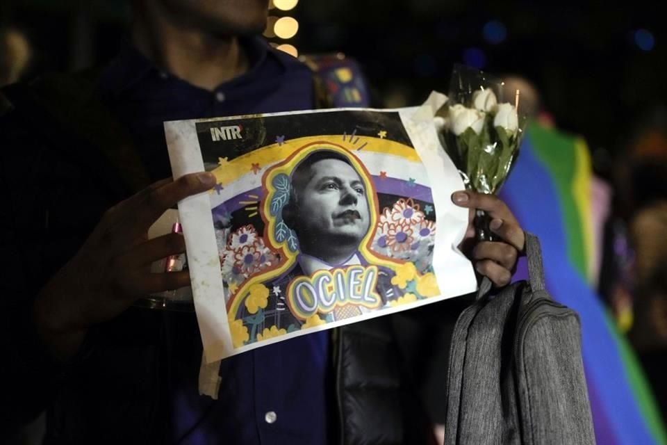 Un manifestante sostiene una fotografía del magistrade del Tribunal Electoral del estado de Aguascalientes Jesús Ociel Baena durante una vigilia tras su muerte, en la Ciudad de México.