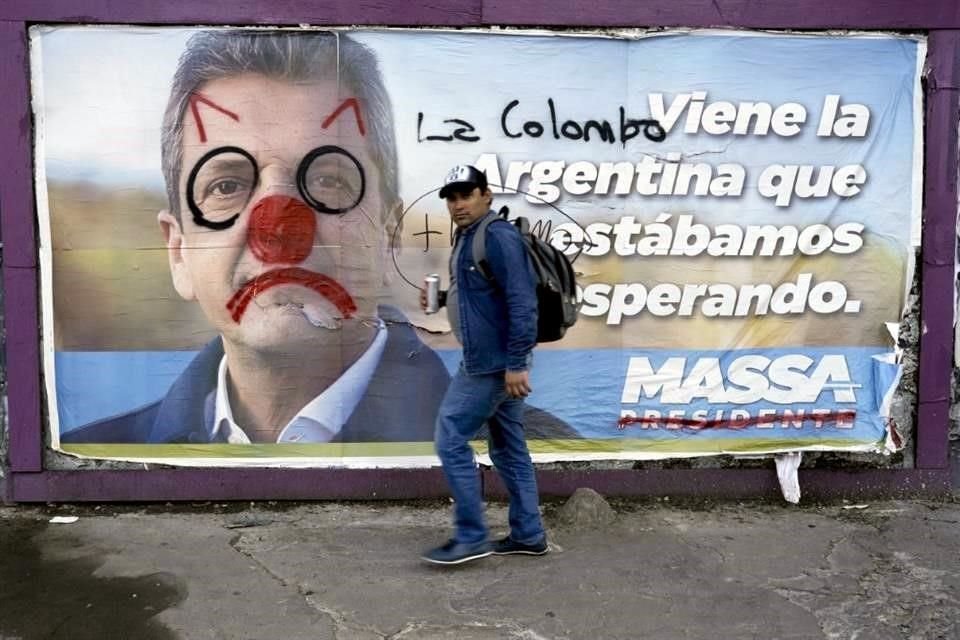 Un hombre pasa junto a un cartel desfigurado del Ministro de Economía, Sergio Massa.