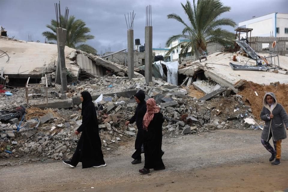 Palestinos caminan junto a escombros causados por ataques israelíes en la Franja de Gaza.
