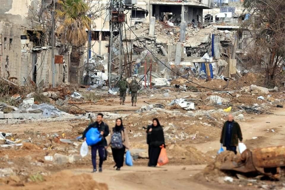 Soldados israelíes pasan junto a palestinos que huyen del norte a lo largo de la carretera Salaheddine en el distrito de Zeitoun.