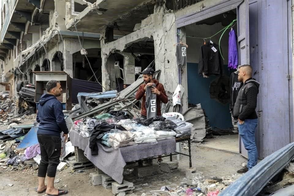 Palestinos venden ropa frente a su tienda destruida en la carretera principal de Beit Lahiya, Franja de Gaza.