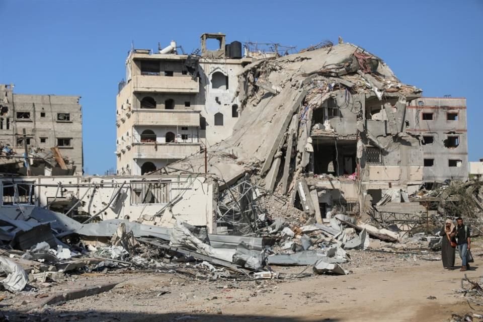 Personas caminan frente a edificios destruidos, en la ciudad de Gaza, el 29 de noviembre de 2023.