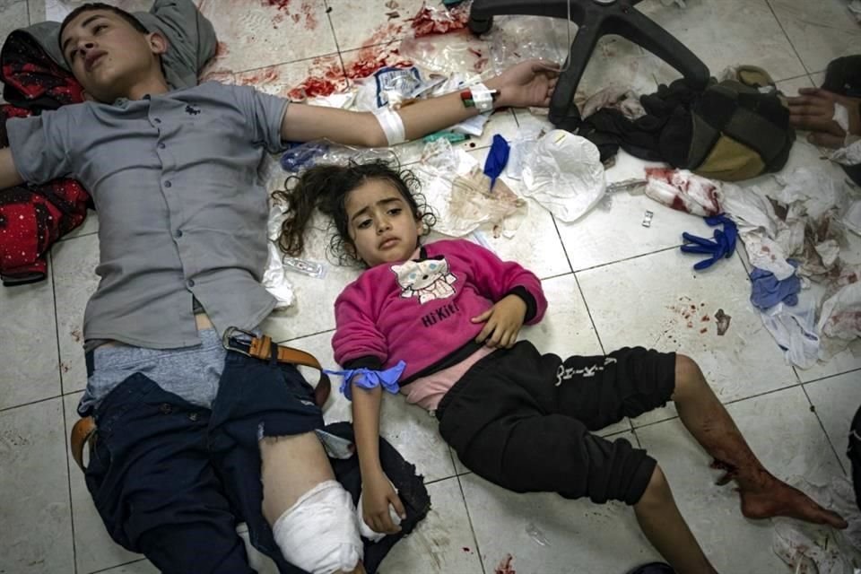 Un niño y una niña esperan ser atendidos en el suelo después de haber sido heridos en un bombardeo del ejército israelí en la Franja de Gaza, en el hospital de Khan Younis.