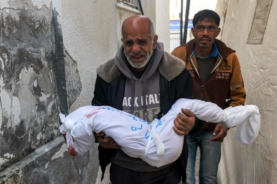 Un palestino de Khan Yunis, sigue a su padre, que lleva el cuerpo envuelto de su hija Sidal, que murió durante la noche mientras dormía en una tienda de campaña a causa de un fragmento de metralla.