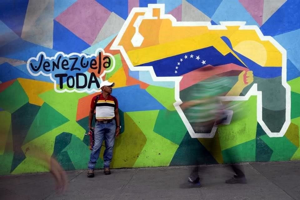 Un hombre vende cables para celulares delante de un mural con un mapa de Venezuela que incluye el territorio de Esequibo, en el vecindario de Petare, en Caracas, Venezuela.