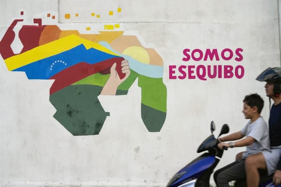 Un niño conduce una motocicleta por delante de un mural con el mapa de Venezuela, que incluye el territorio de Esequibo, en Caracas el 11 de diciembre de 2023.