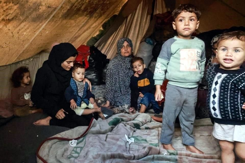 Los palestinos descansan en su tienda de campaña improvisada en un campamento instalado en el patio de una escuela en Rafah.