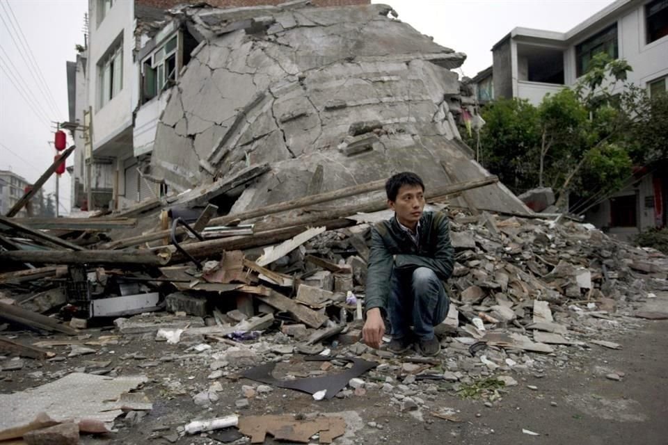 Un hombre se agacha cerca de los restos derrumbados de un edificio destruido por un terremoto en el condado de Lushan en la provincia de Sichuan, suroeste de China.