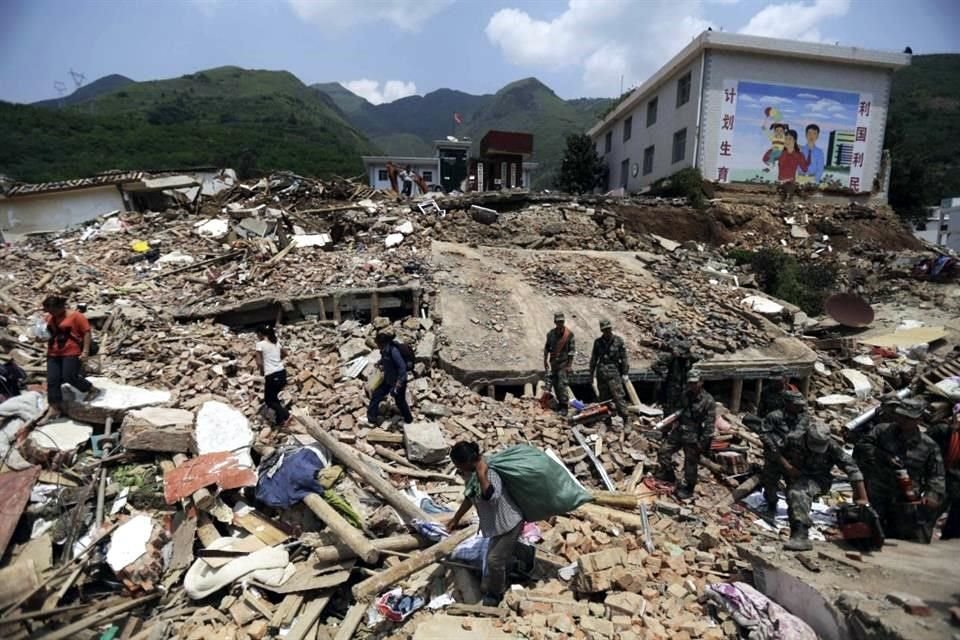 Los aldeanos recorren los escombros de las casas destruidas mientras los rescatistas buscan personas desaparecidas en la ciudad de Longtoushan.