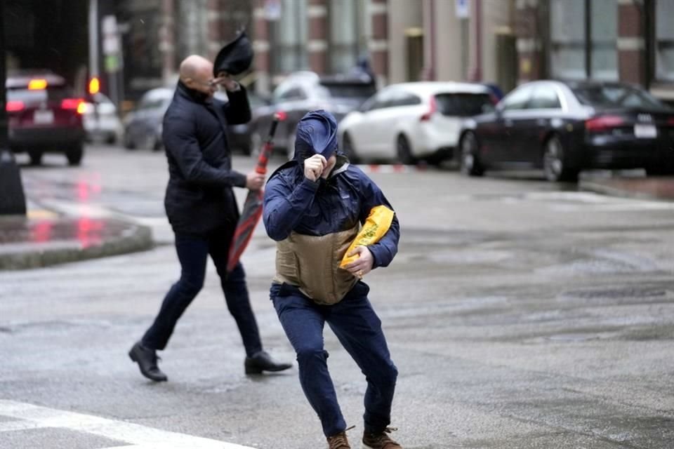 Los peatones son azotados por el viento al cruzar una calle en Boston.