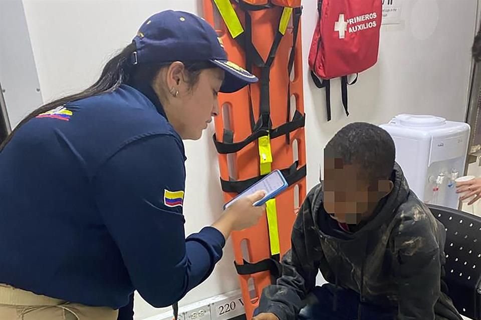 Una agente de migración habla con un menor tras ser encontrado solo en el aeropuerto de Bogotá.