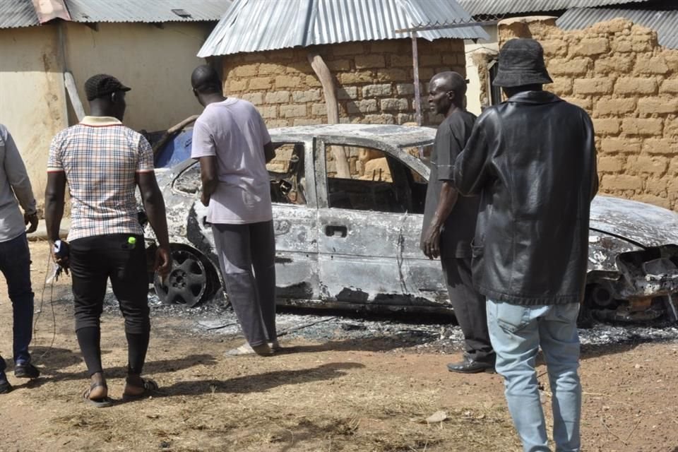 Personas junto a un auto quemado tras un ataque en Bakkos, Nigeria, el 26 de diciembre.