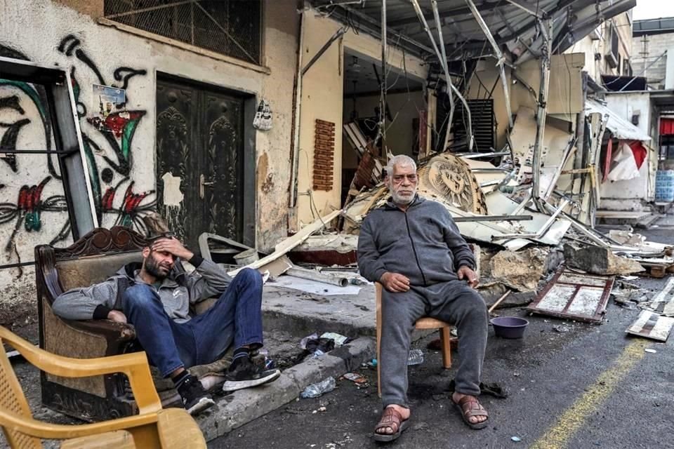 Hombres palestinos sentados junto a los escombros frente a un edificio dañado después de una incursión israelí en el campamento de refugiados palestinos en la Cisjordania ocupada.