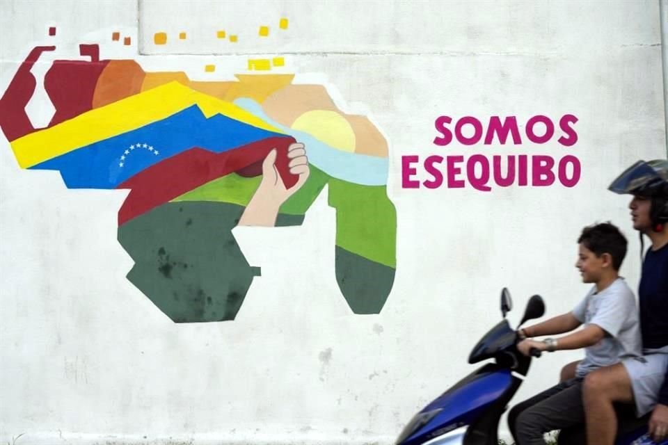 Un niño conduce una motocicleta por delante de un mural con el mapa de Venezuela, que incluye el territorio de Esequibo.