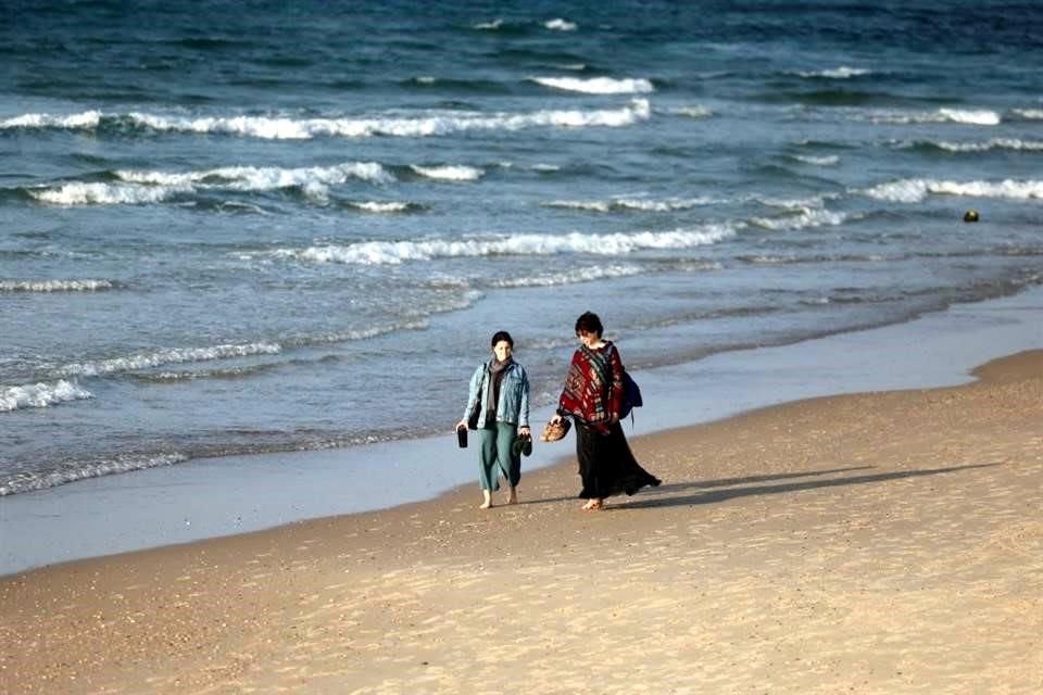 Mujeres caminan por la playa en la ciudad costera israelí de Tel Aviv, en medio de continuas batallas entre Israel y el grupo militante palestino Hamas en la Franja de Gaza.