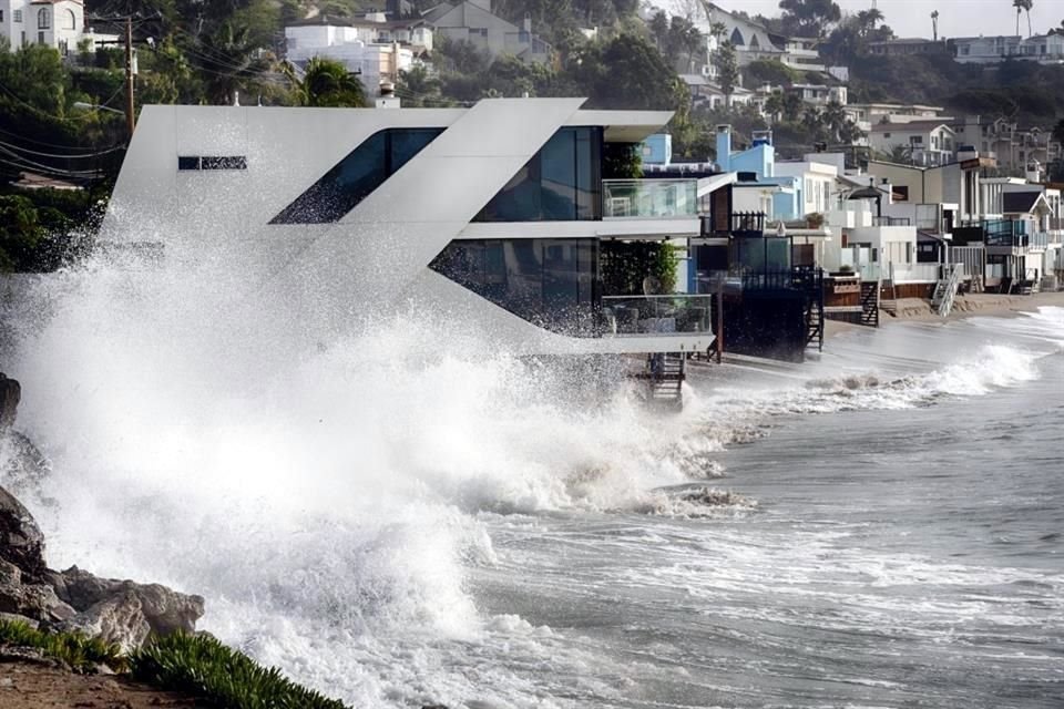 Las olas rompen contra una casa a lo largo de la costa de California en Malibu Beach, California.