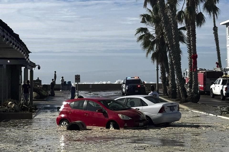 Las excavadoras construyeron bermas de arena gigantes el viernes para proteger las casas frente a la playa en una de las ciudades de California más afectadas esta semana.