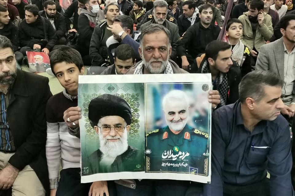 Un hombre muestra los retratos del líder supremo de Irán, el Ayatolá Alí Jamenei, y del General Qassem Soleimani durante las ceremonia para conmemorar el asesinato del segundo.