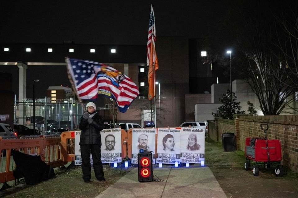 Una mujer sostiene una bandera durante una vigilia por el seis de enero, afuera de la cárcel de Washington.