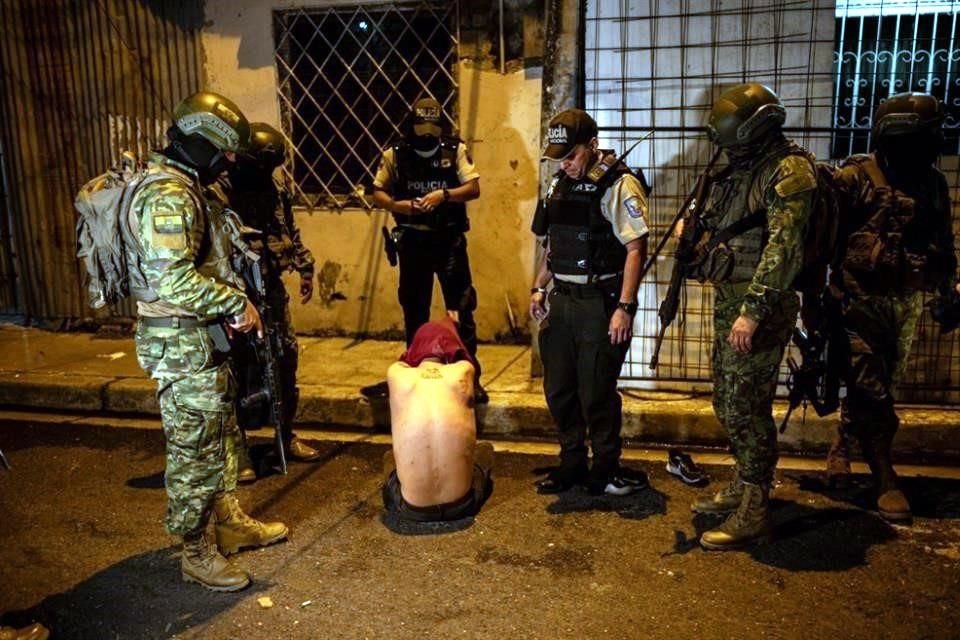 Soldados mantienen detenido a un hombre mientras participan con agentes de policía en un operativo de seguridad y búsqueda de sospechosos durante el toque de queda en barrios pobres de Guayaquil.