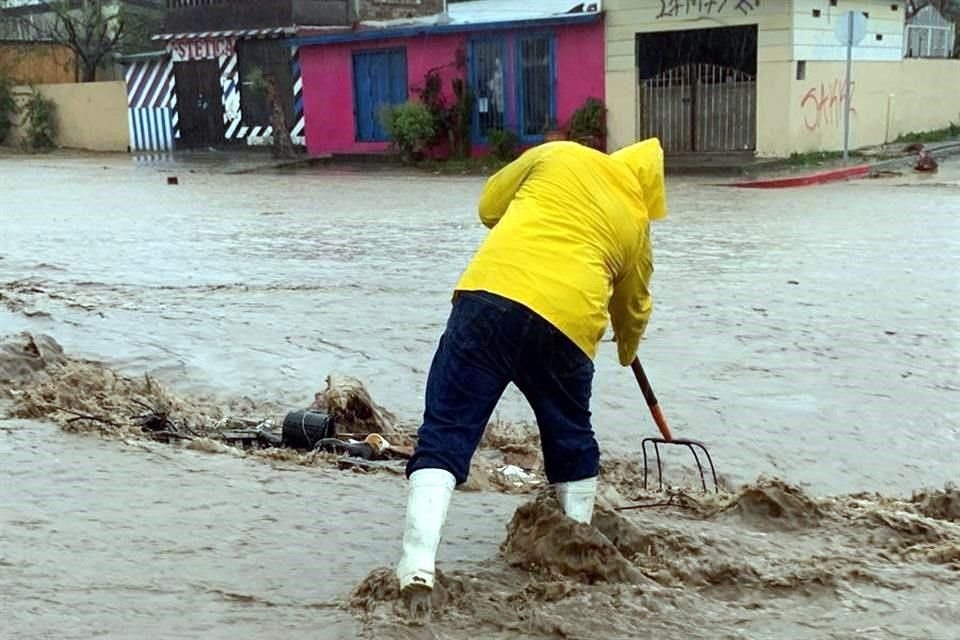 Bomberos y Protección Civil laboran en el desazolve del drenaje.