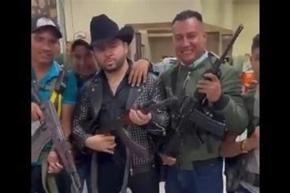 El cantante Larry Hernández (centro, con sombrero negro) desató polémica por posar con armas.