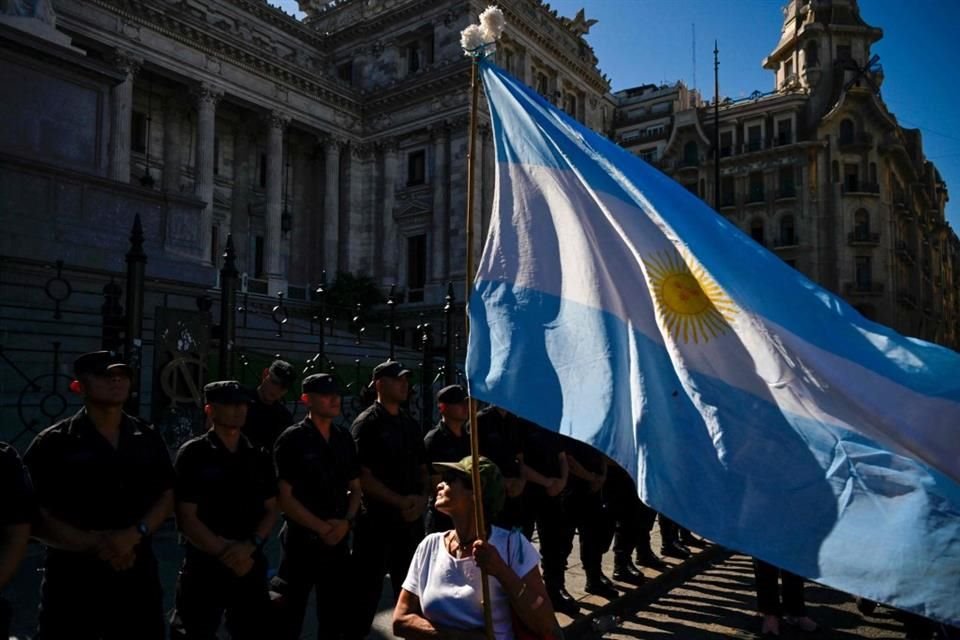 Una mujer sostiene una bandera de Argentina frente a una fila de policías afuera del Congreso, en Buenos Aires.