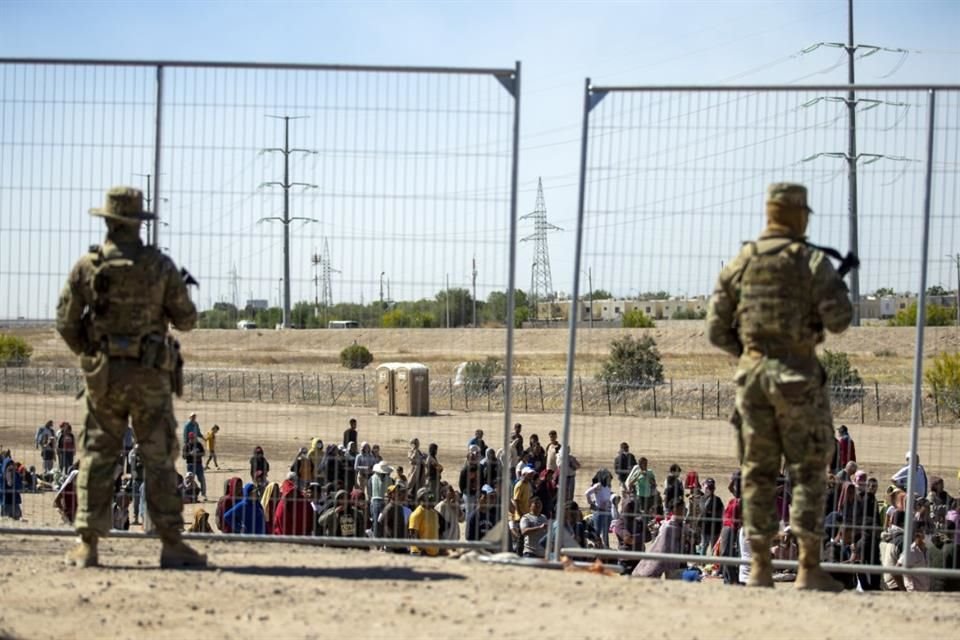 Migrantes hacen fila frente a una valla fronteriza bajo la vigilancia de la Guardia Nacional de Texas, en El Paso, el 10 de mayo del 2023.