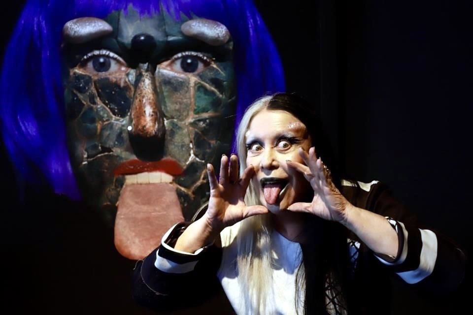 ORLAN posa frente a la fotografía de una máscara de jade precolombina, digitalmente modificada para implantar sus facciones, parte de la serie 'Hibridaciones'.