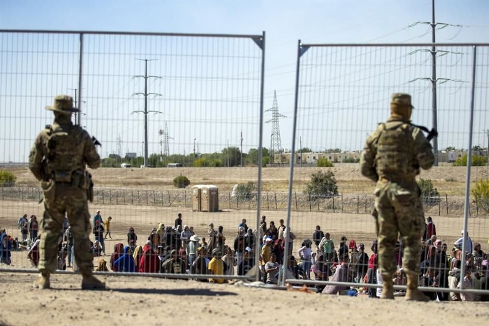 Migrantes esperan a un lado de una cerca fronteriza custodiada por la Guardia Nacional de Texas, en El Paso, el 10 de mayo del 2023.