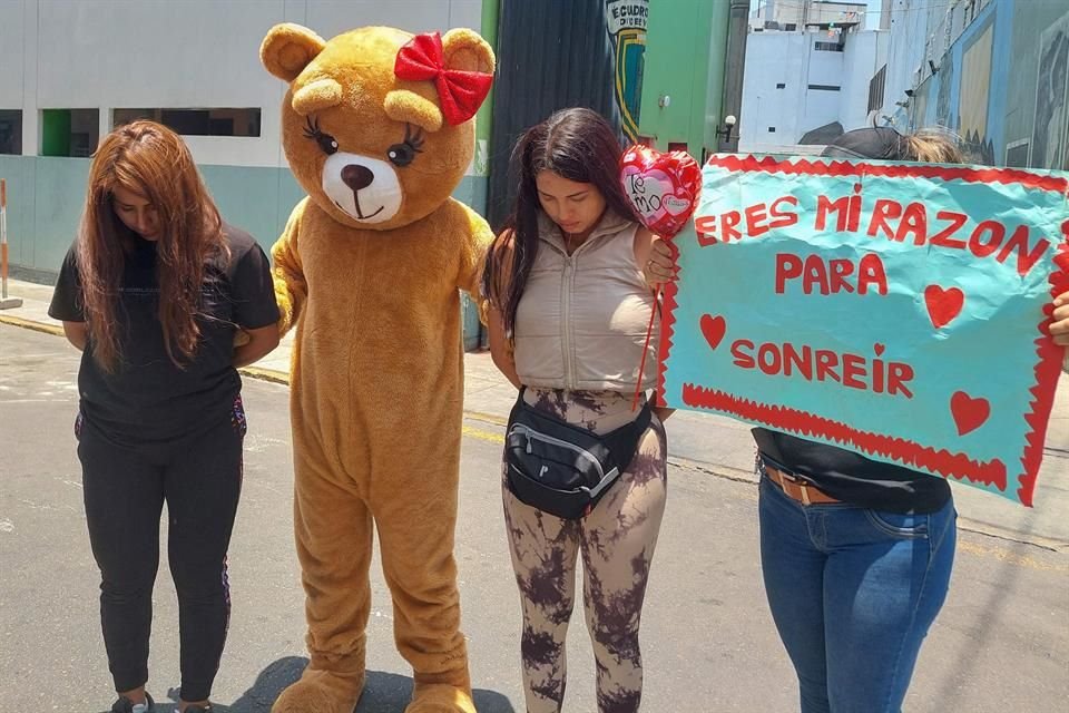 El policía disfrazado de oso posa con las detenidas y el cartel que utilizó en el operativo.