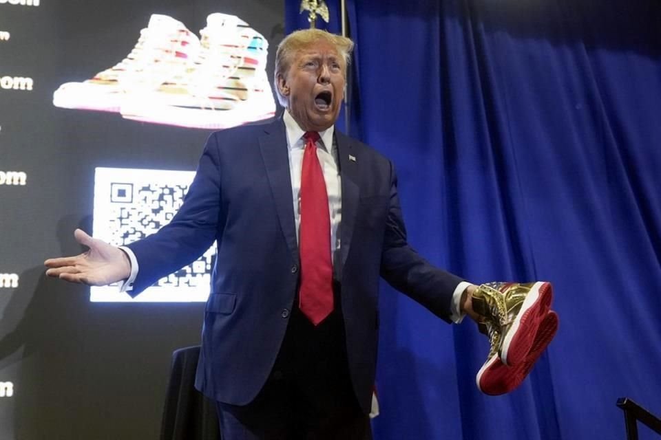 El candidato presidencial republicano, el expresidente Donald Trump, sostiene zapatillas doradas de Trump en Sneaker Con Filadelfia.