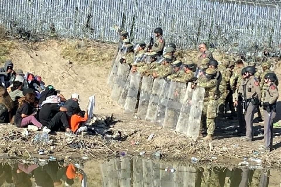 Migrantes que persisten se colocaron sentados frente a los elementos en señal de paz e incluso mostraron una bandera blanca.