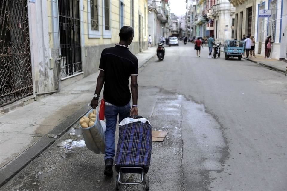 Un hombre lleva un carro de la compra con una bolsa llena de pan, en La Habana, Cuba.