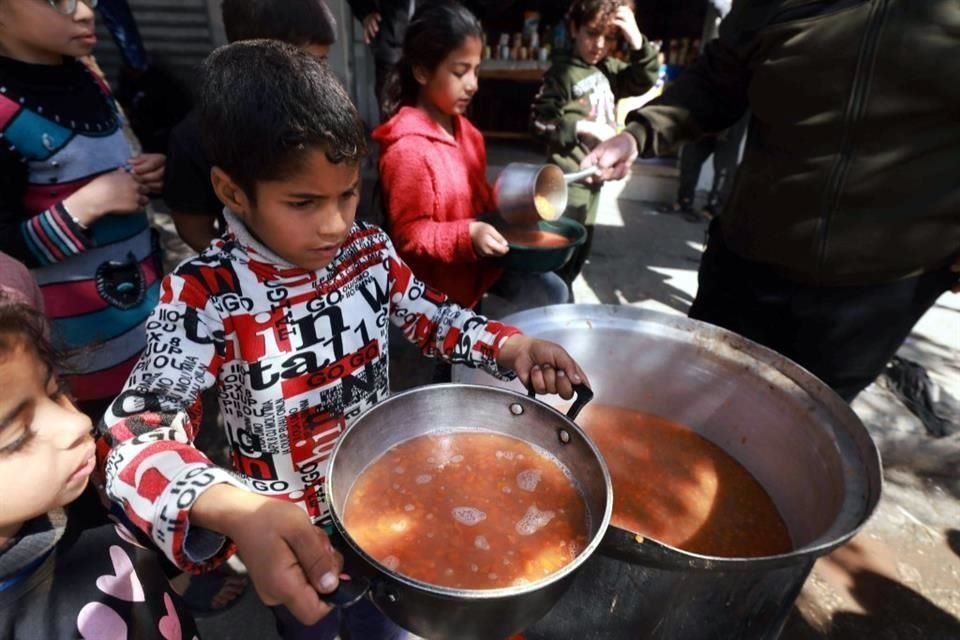 Los niños palestinos reciben raciones de comida cocinada como parte de una iniciativa juvenil voluntaria en Rafah.