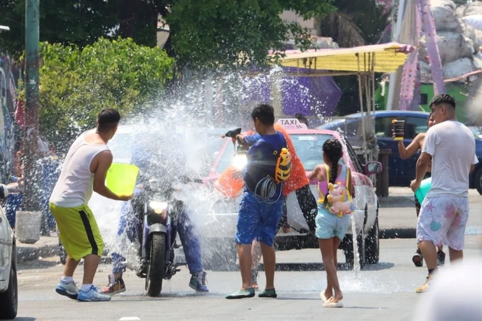 Una familia adquirió un brincolín con cascadas de agua y una pequeña alberca para refrescarse, con cubetadas y pistolas de presión.