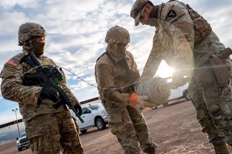 Soldados de la Guardia Nacional de Texas desenrollan un rollo de alambre de concertina en preparación para construir una valla fronteriza cerca del río Bravo.