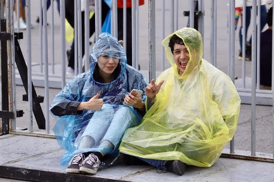 Muchos asistentes portan ponchos impermeables por la intermitente lluvia.