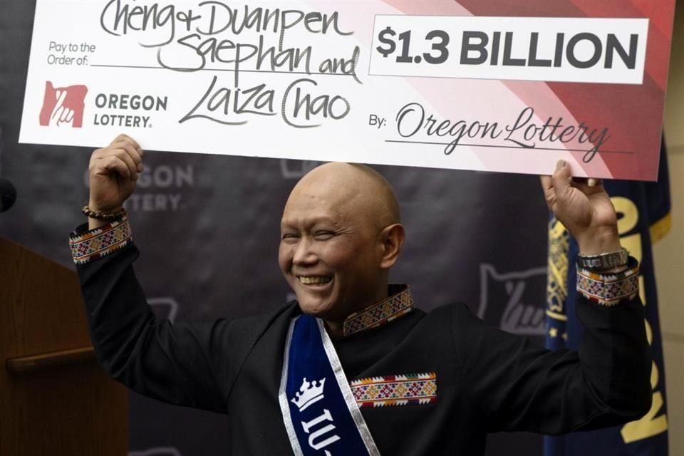 Cheng Saephan levanta feliz un cheque en las oficinas de la Lotería de Oregon, tras ganar el premio de Dls. 1,300 millones.