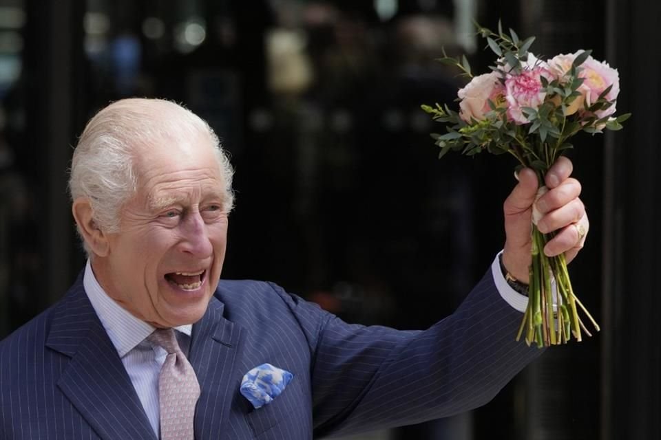 Carlos III de Gran Bretaña sostiene las flores que le regalaron al salir después de una visita al Centro de Cáncer Macmillan del University College Hospital en Londres