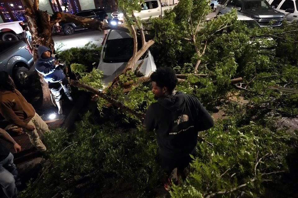 Miembros de Relief Gang ayudan a retirar ramas de árboles caídas de automóviles aplastados después de una fuerte tormenta que pasó por el centro de Houston.