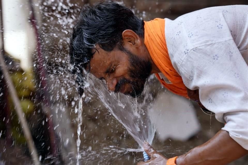 Un hombre se moja el rostro con agua de un grifo en la calle para refrescarse en un día de mucho calor en Lucknow, India.