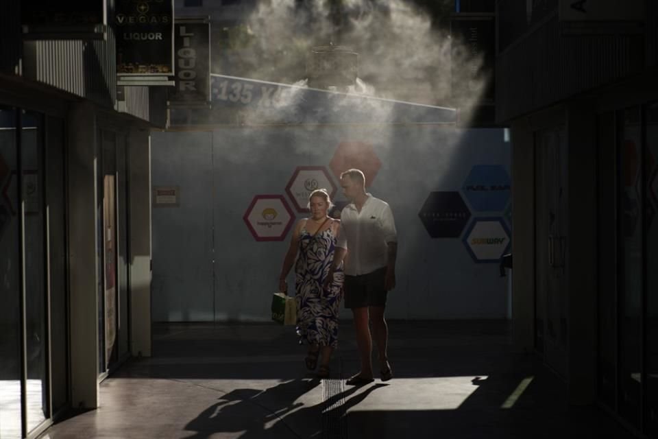 Personas caminan a través de una bruma refrescante en Las Vegas, el 13 de julio del 2023.