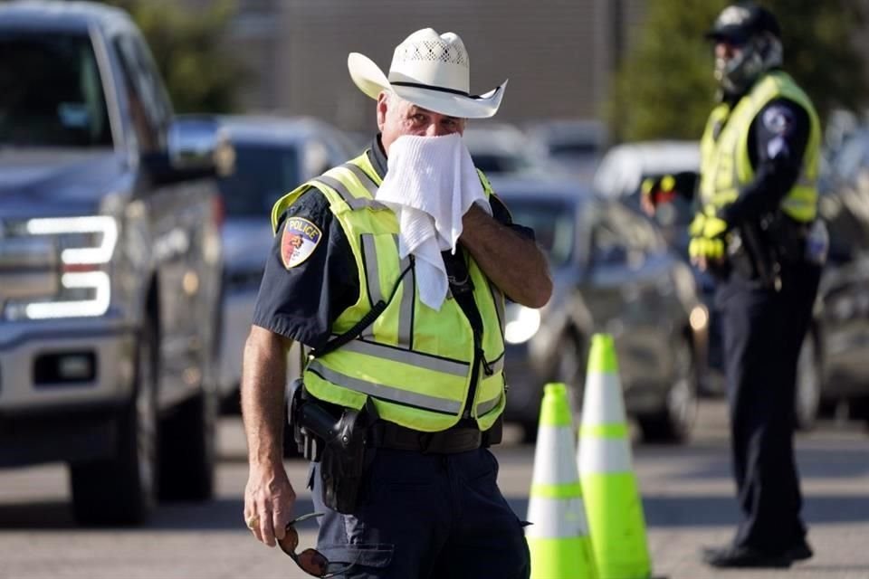 El oficial de policía James Rhodes usa una toalla mojada para refrescarse mientras dirige el tráfico después de un evento deportivo en Arlington, Texas.