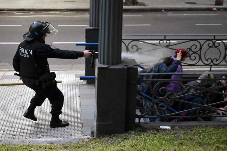 Un policía antidisturbios usa un gas pimienta contra manifestantes en Argentina.