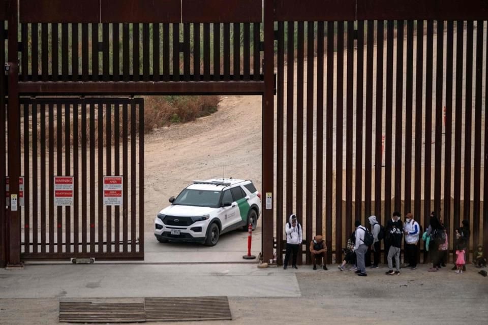 Migrantes y solicitantes de asilo esperan a ser procesados por la Patrulla Fronteriza en la frontera entre México y Estados Unidos.