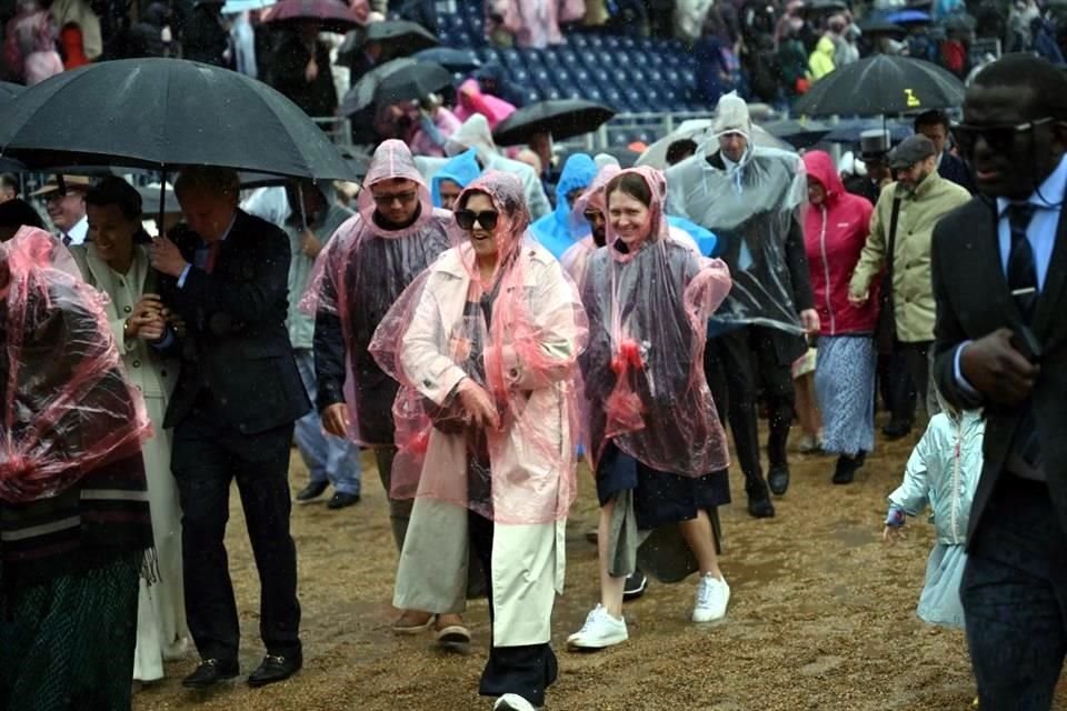 Los fanáticos de la realeza que asistieron al lugar tuvieron que cubrirse de la copiosa lluvia.