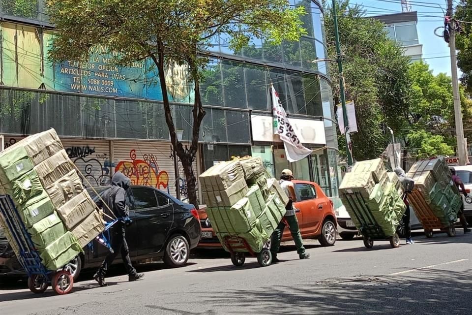 Un ejército de los denominados 'diableros' acarrean las cajas desde los tráileres hasta las plazas. La presencia de estos trabajadores comenzó a proliferar tras la pandemia.  