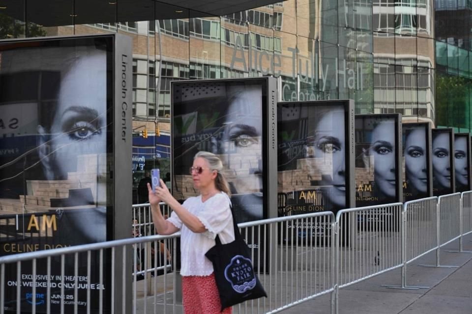 Una persona toma fotografías de los carteles digitales 'I Am: Celine Dion'  frente al Alice Tully Hall en Nueva York