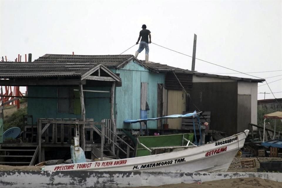 Un hombre realiza trabajos en su casa para prepararse para la tormenta en la Playa Bagdad, en Matamoros.